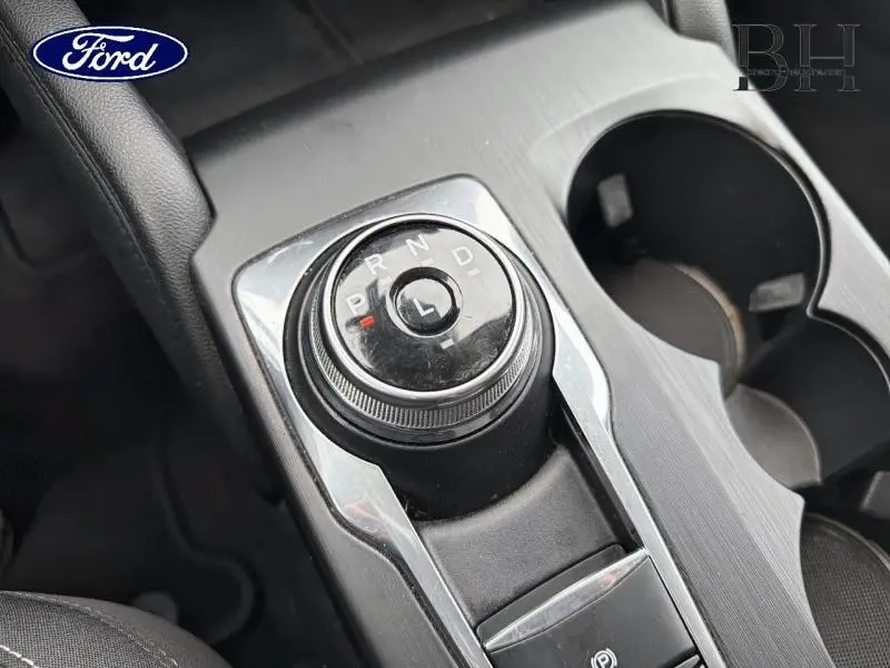 Gros plan sur la molette de sélection de vitesse de la boîte automatique du Ford Kuga, intérieur noir avec console grise.