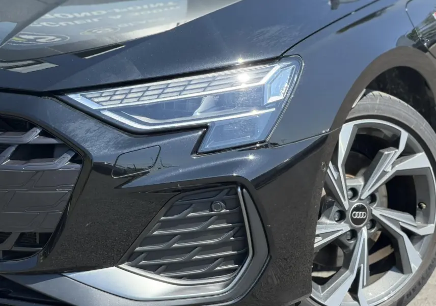 Gros plan sur l'avant droit noir Mythe de l'Audi A3 Sportback 2025 avec phares Matrix LED et jante alliage 5 branches en Y.