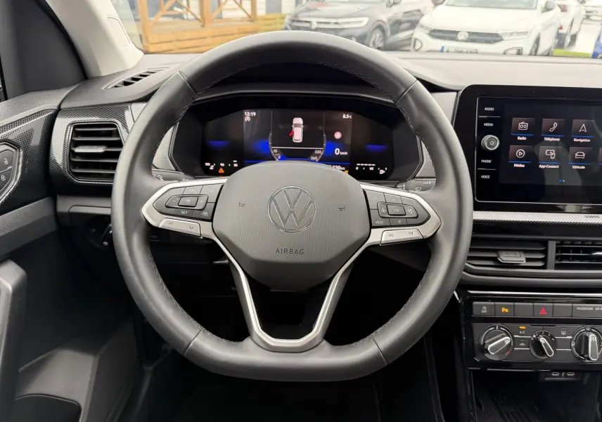 Vue intérieure centrée sur le volant multifonction cuir et le tableau de bord digital du Volkswagen T-Cross 2025.