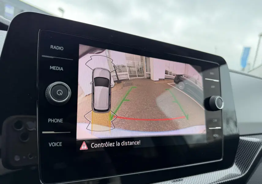 Écran tactile intérieur montrant la caméra de recul avec guidage visuel du Volkswagen T-Cross bleu.