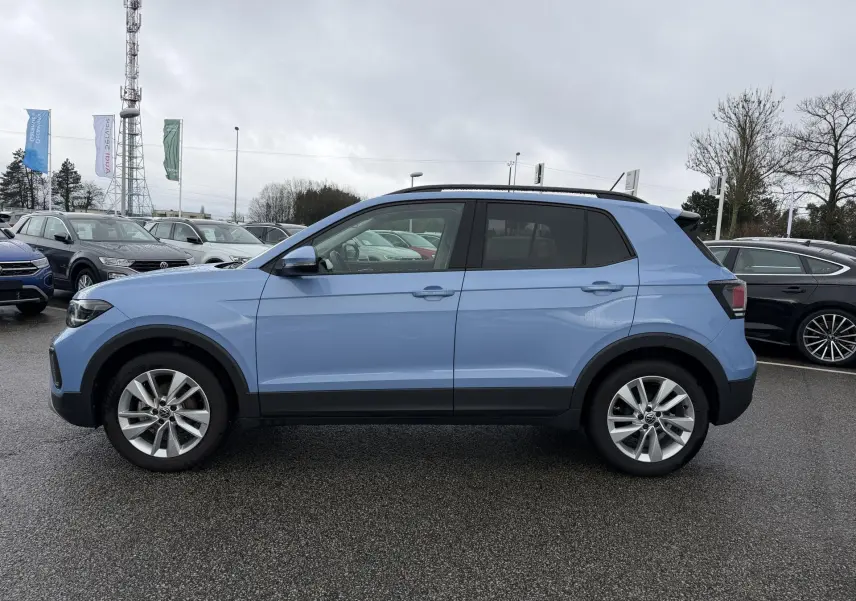 Volkswagen T-Cross bleu en vue profil côté gauche, avec jantes alliage 17 pouces et vitres surteintées.