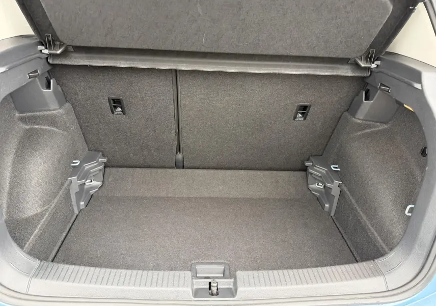 Coffre ouvert du Volkswagen T-Cross bleu, vue intérieure montrant l'espace de chargement et les fixations ISOFIX.