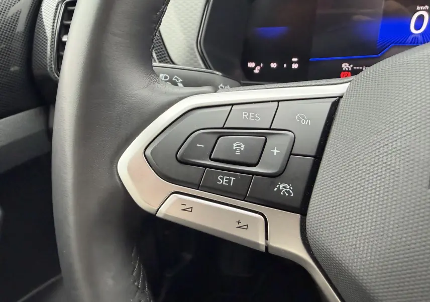Gros plan sur le volant cuir du Volkswagen T-Cross 2025, avec commandes du régulateur de vitesse adaptatif visibles.