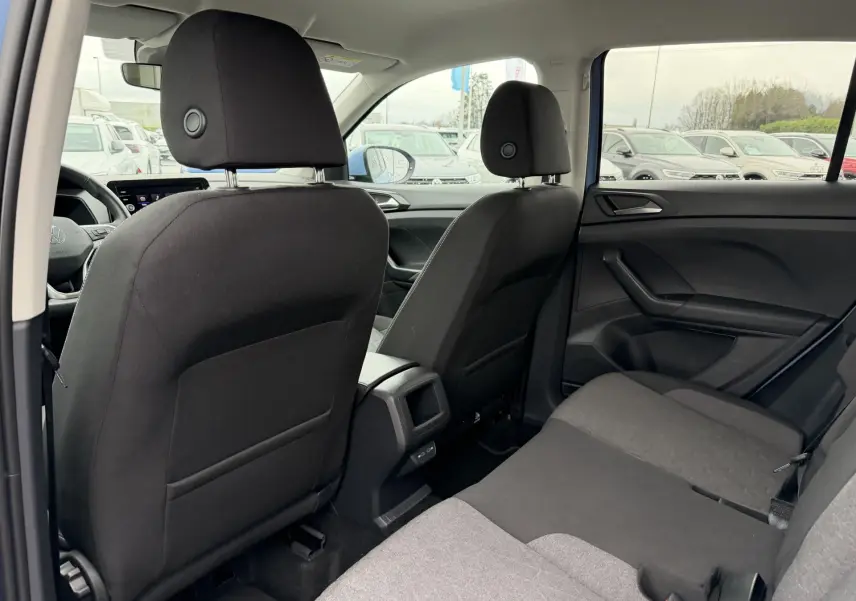 Vue intérieure arrière du Volkswagen T-Cross 2025 montrant les sièges tissu noirs et la console centrale entre les sièges avant.