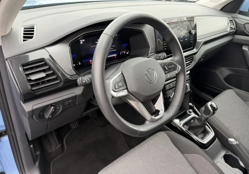 Vue intérieure côté conducteur du Volkswagen T-Cross bleu 2025, volant cuir multifonction et boîte manuelle visible.
