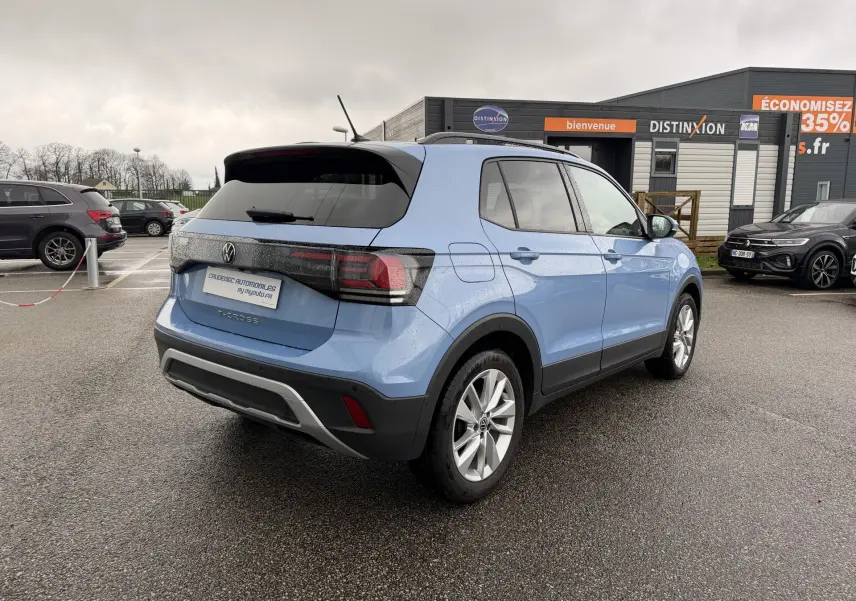 Vue 3/4 arrière droite d'un Volkswagen T-Cross bleu avec jantes alliage 17 pouces et vitres surteintées.