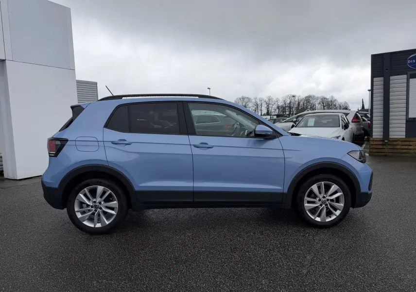 Vue latérale droite d'un Volkswagen T-Cross bleu clair avec jantes alliage et vitres surteintées.