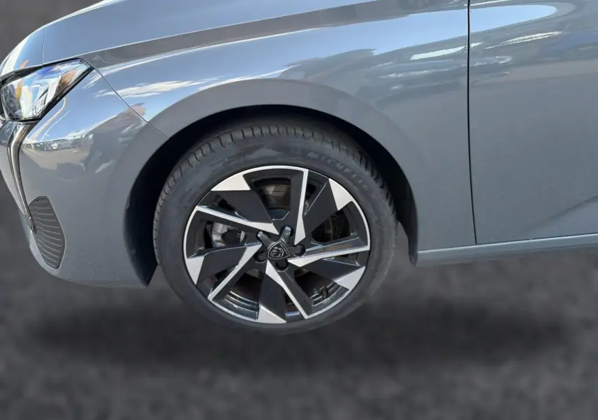 Gros plan sur la roue avant gauche et l'aile d'une Peugeot 308 gris selenium, mettant en valeur la jante alu design.