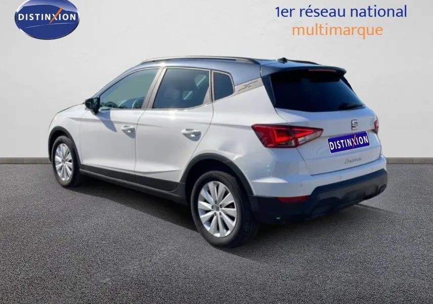 Vue 3/4 arrière droite d'une SEAT Arona blanche métal avec toit noir, sur fond neutre en extérieur.