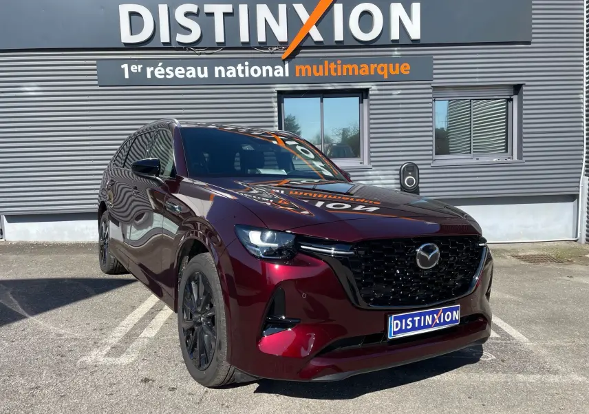 Vue 3/4 avant du Mazda CX-80 hybride rechargeable en rouge Artisan, avec calandre noire et jantes foncées.