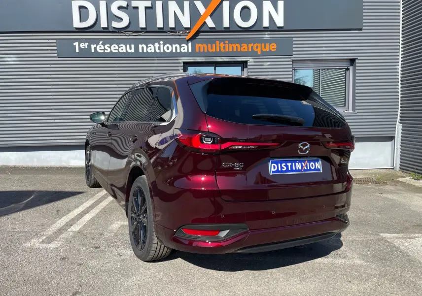 Vue 3/4 arrière droite du Mazda CX-80 hybride rechargeable en rouge Artisan, avec feux arrière LED et jantes noires.