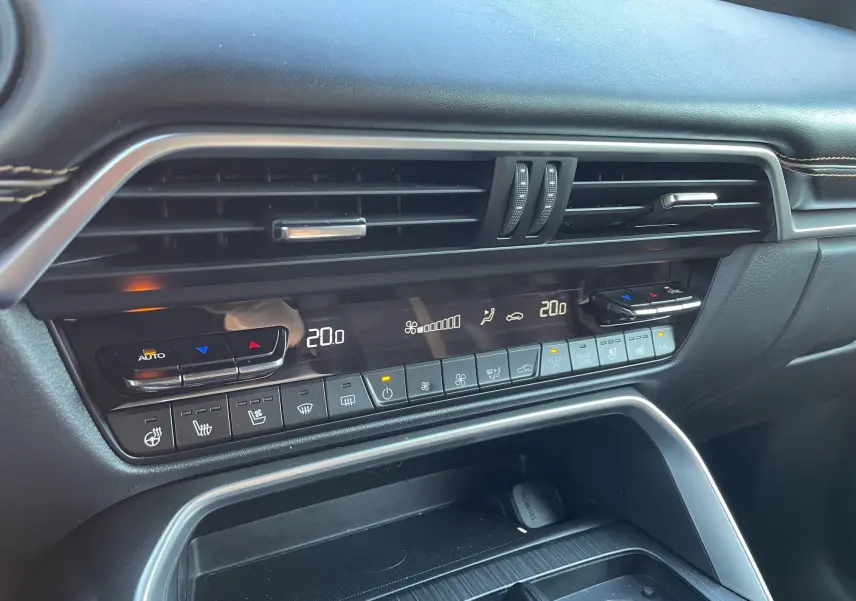 Vue rapprochée de la console centrale noire du Mazda CX-80 2024 avec commandes climatisation digitales et finition cuir.
