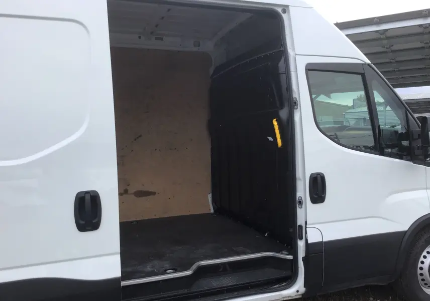 Vue latérale droite d’un Iveco Daily Fourgon blanc 2023 avec porte coulissante ouverte montrant l’espace de chargement vide.