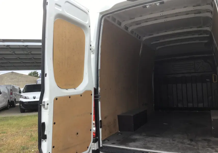 Vue arrière ouverte du fourgon Iveco Daily blanc 2023, montrant l’intérieur cloisonné avec revêtement bois.