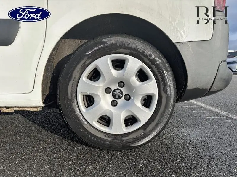 Gros plan sur la roue arrière droite d’un Peugeot Partner Tepee blanc Banquise, avec jante acier et logo Peugeot central.