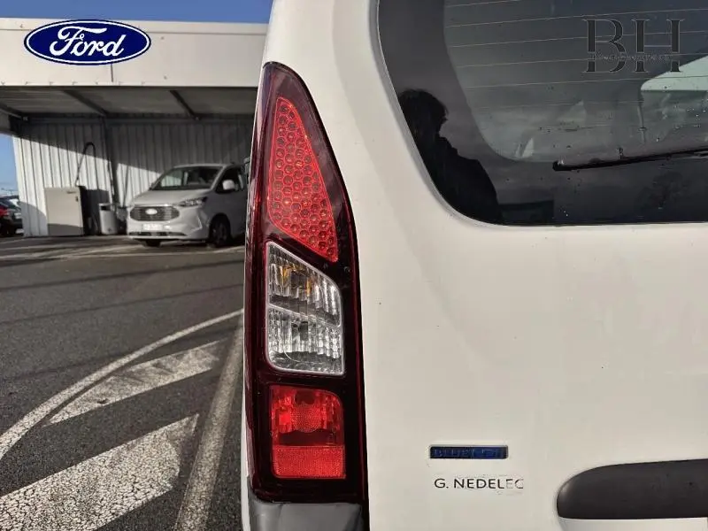 Gros plan sur le feu arrière droit du Peugeot Partner Tepee blanc banquise, avec logo et hayon visible.