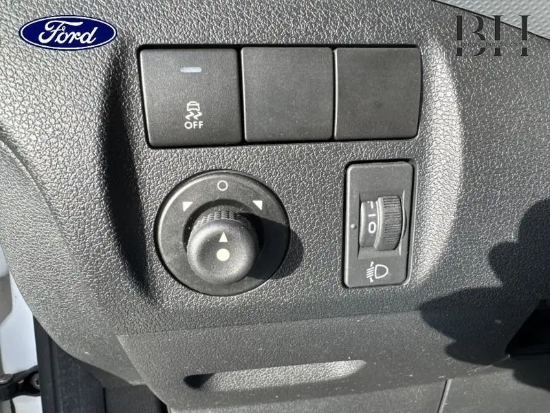Gros plan sur les commandes de réglage des rétroviseurs et des phares du Peugeot Partner Tepee blanc, côté conducteur.