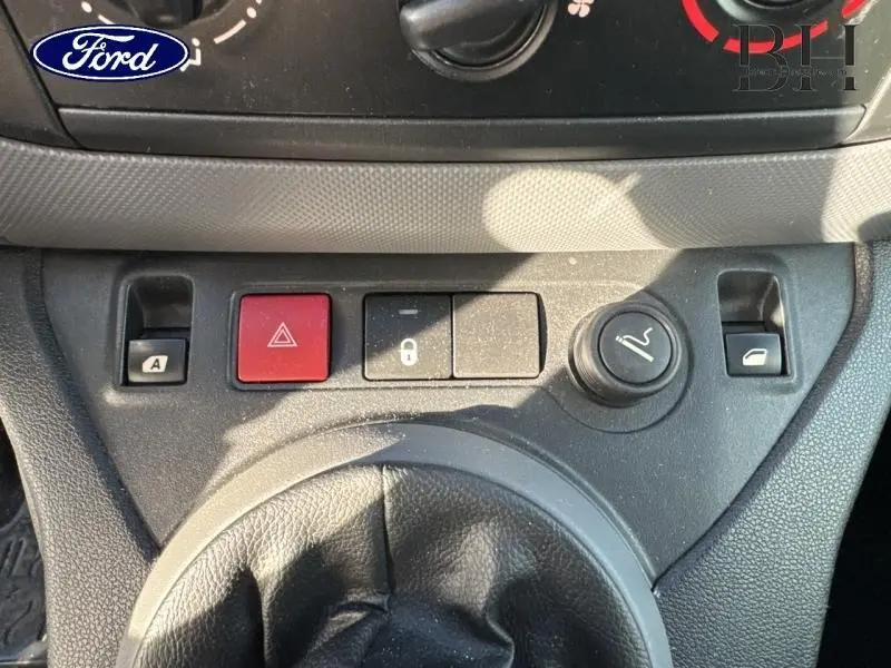 Gros plan sur la console centrale noire avec boutons de verrouillage, warning et allume-cigare d’un Peugeot Partner Tepee blanc.