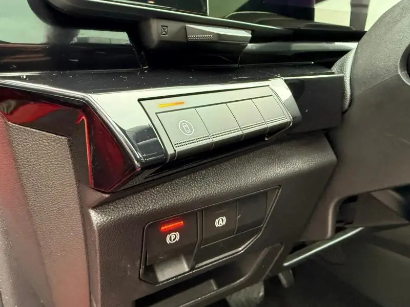 Gros plan sur les commandes de verrouillage et frein à main électronique du Renault Austral 2025, intérieur noir avec reflet rouge flamme.