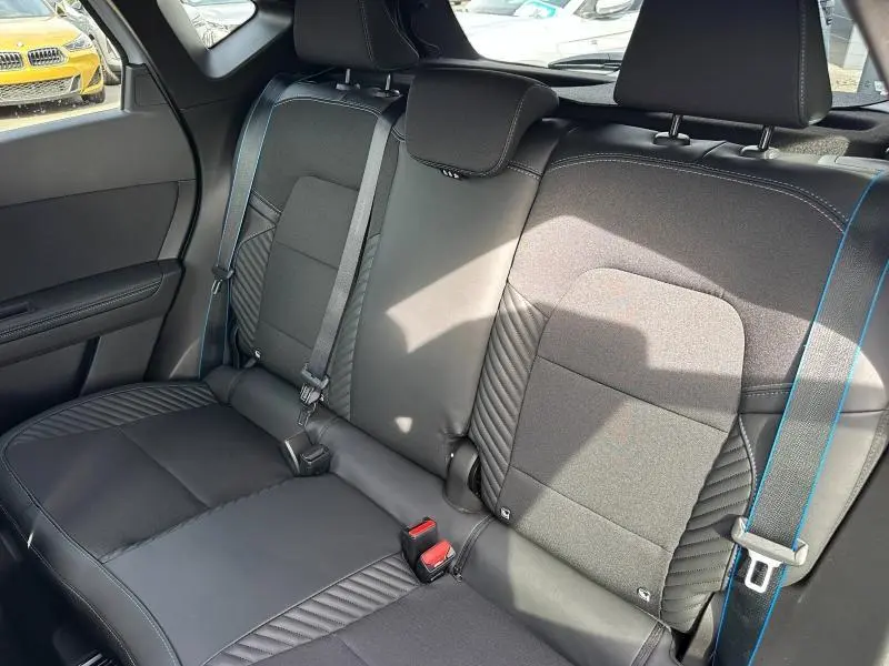 Vue intérieure arrière du Renault Captur 2026, sièges noirs avec surpiqûres bleues et ceintures assorties.