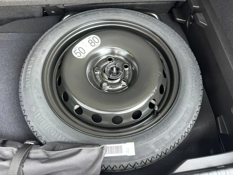 Roue de secours noire en acier dans le coffre du Renault Captur 2026 gris Cassiopée/Noir Étoilé, vue de dessus.