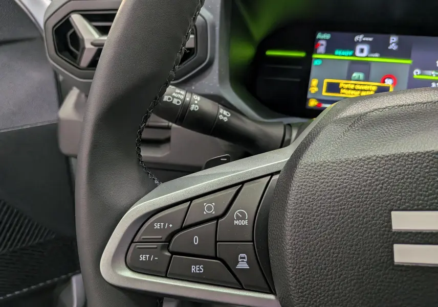 Gros plan sur le volant noir du Dacia Duster Hybrid-G 150 CH 4x4 2026 avec commandes de régulateur et tableau de bord numérique.