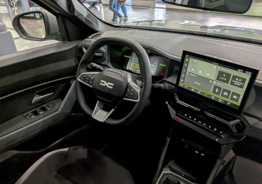 Vue intérieure côté conducteur du Dacia Duster Hybrid-G 150 CH 4x4 2026, avec tableau de bord numérique et écran tactile central.