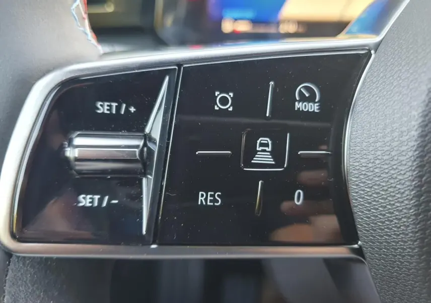 Gros plan sur les commandes de régulateur de vitesse au volant d’une Renault Clio VI hybride.