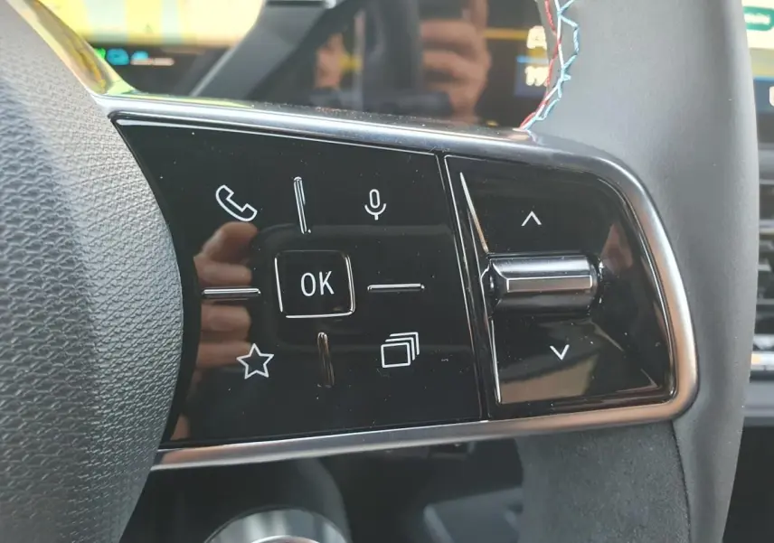 Gros plan sur les commandes multifonctions du volant de la Renault Clio VI, finition Esprit Alpine, avec surpiqûres bleues.