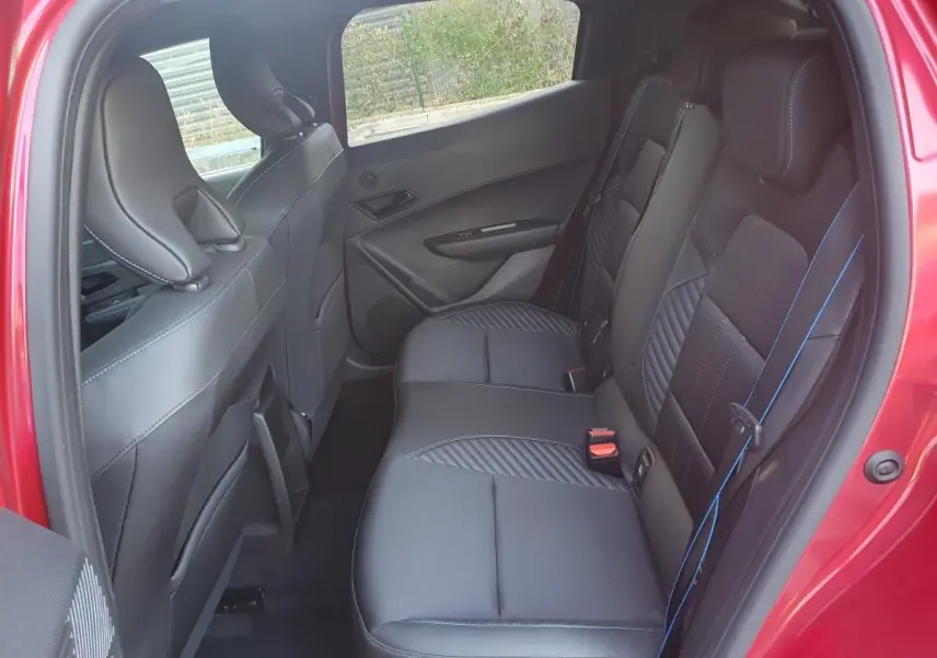 Vue intérieure côté droit des sièges arrière en tissu noir avec surpiqûres bleues d'une Renault Clio VI rouge absolu.
