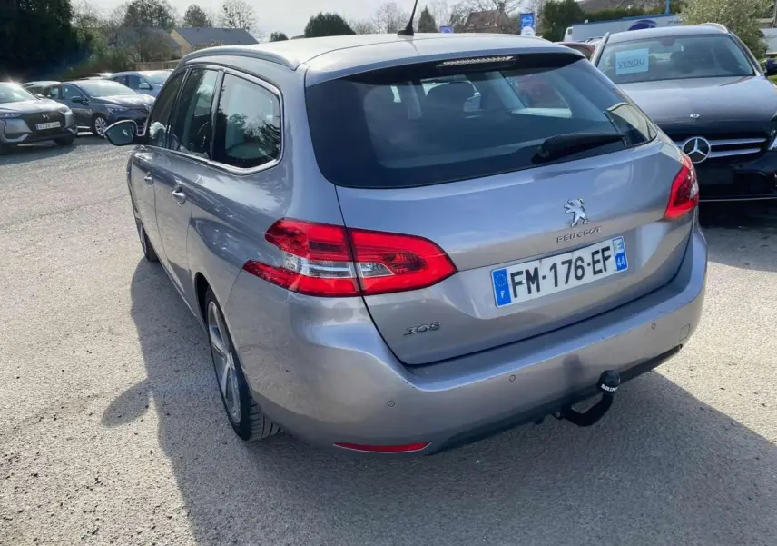 Vue 3/4 arrière droite d'une Peugeot 308 SW gris Artense métallisé avec attelage de remorque visible.