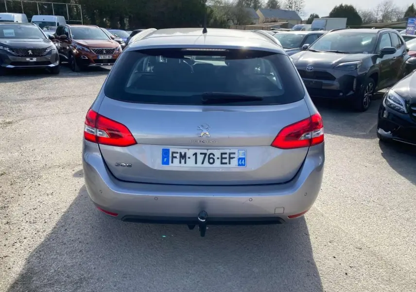 Vue arrière d'une Peugeot 308 SW gris Artense métallisé de 2019 avec attelage visible en stationnement extérieur.