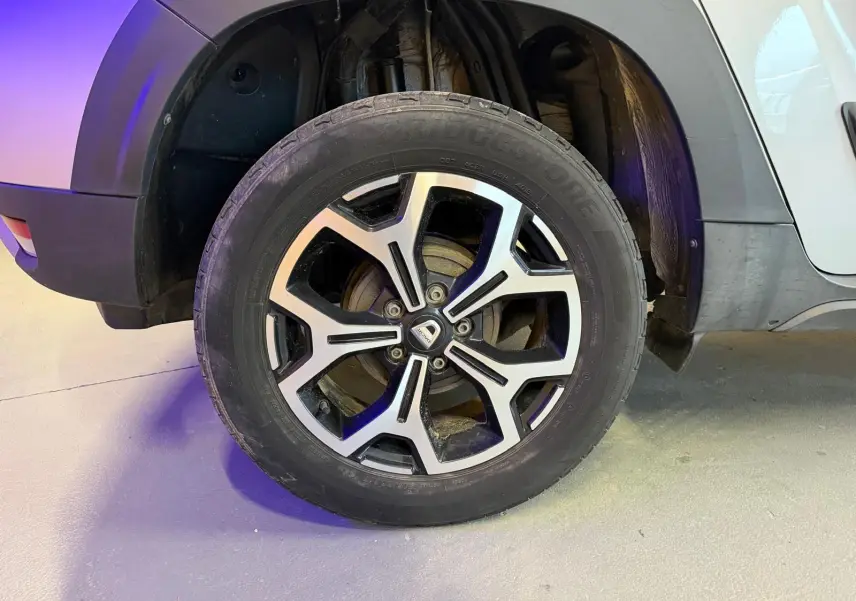 Gros plan sur la roue avant droite du Dacia Duster gris 2019 avec jante alliage 17'' Maldives et logo central.