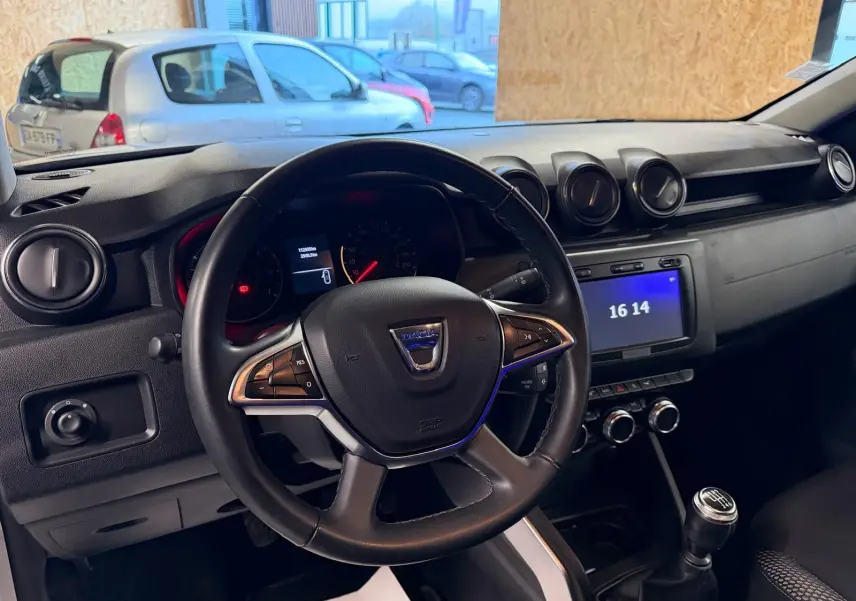 Intérieur du Dacia Duster gris 2019, vue du poste de conduite avec volant, tableau de bord et levier de vitesse manuel.