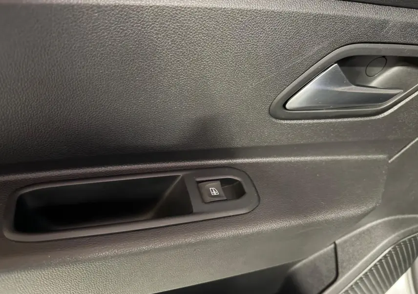Gros plan sur la poignée intérieure et le bouton de lève-vitre côté gauche d'une porte de Dacia Duster gris.