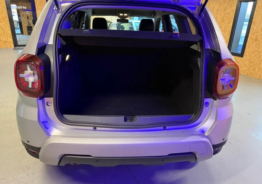 Coffre ouvert vu de l'arrière d'un Dacia Duster gris 2019 avec hayon et feux arrière caractéristiques visibles.