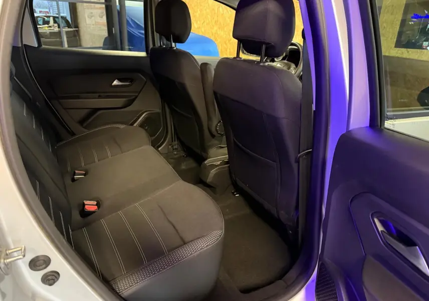 Vue intérieure côté droit sur la banquette arrière noire du Dacia Duster gris, avec portes ouvertes et sièges avant visibles.