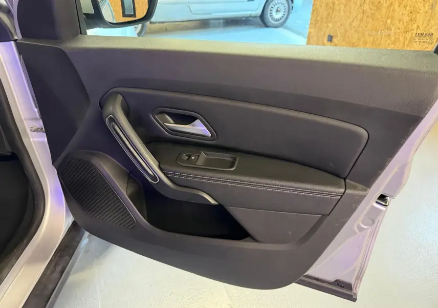 Vue intérieure côté gauche de la porte avant gris clair du Dacia Duster 2019 avec poignée et commande de vitre électrique