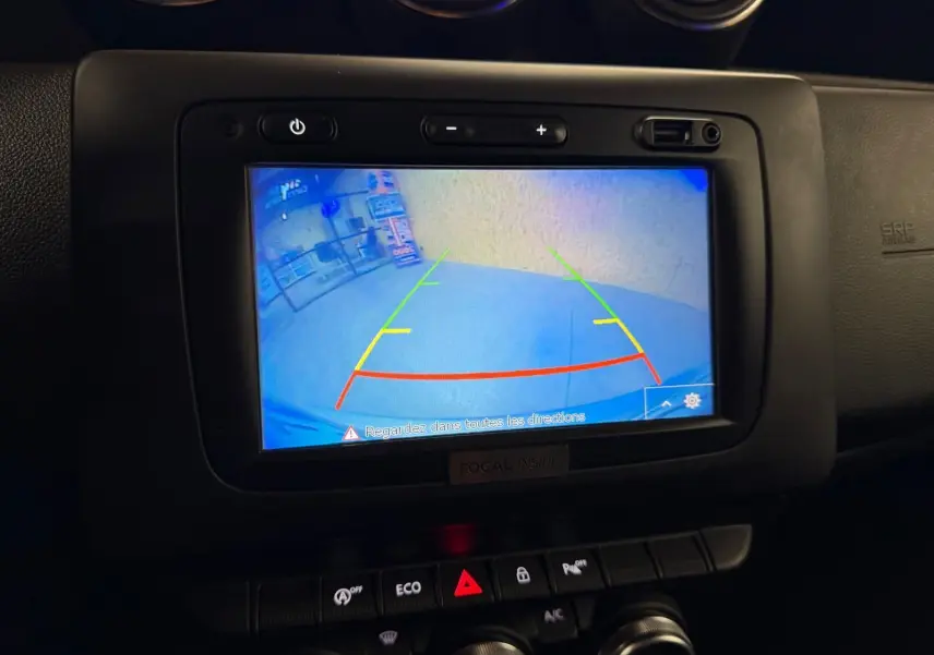 Écran de caméra de recul du Dacia Duster 2019 affichant les lignes de guidage colorées dans l'habitacle noir.