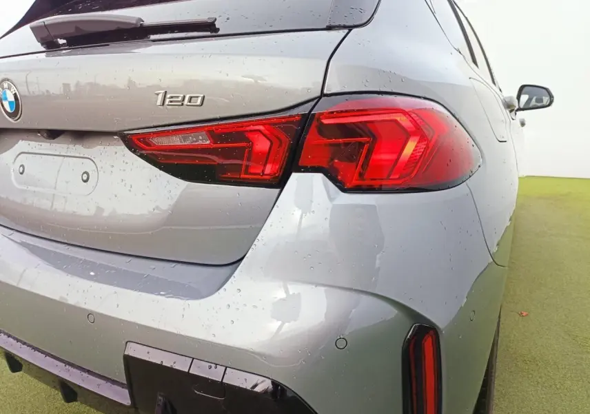 Vue 3/4 arrière droit d'une BMW Série 1 120 M Sport gris Skyscraper avec toit noir et feux arrière LED distinctifs.