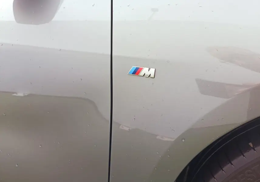 Gros plan sur l'aile avant droite grise Skyscraper d'une BMW Série 1 M Sport avec logo M coloré visible.