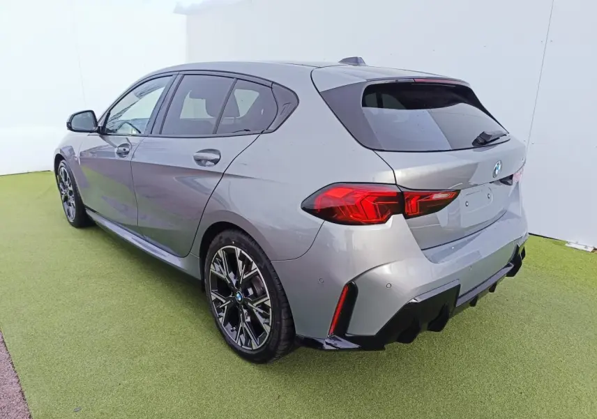 BMW Série 1 gris Skyscraper vue 3/4 arrière droit, toit noir, jantes 18 pouces bicolores et diffuseur arrière noir.