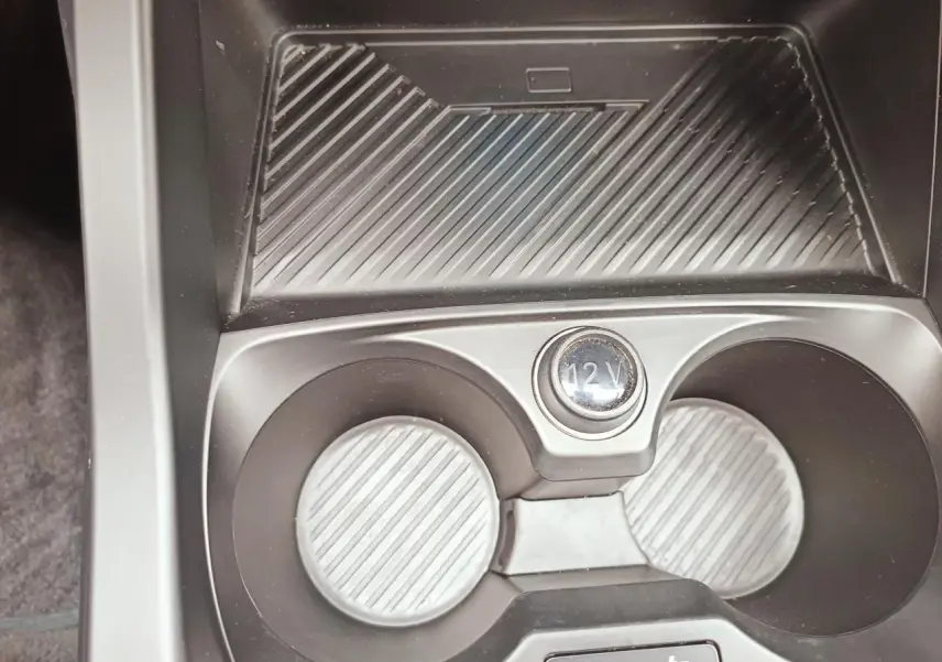 Gros plan sur la console centrale de la BMW Série 1 F70 120 M Sport, montrant les porte-gobelets et prise 12V.