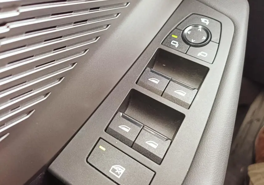 Gros plan sur les commandes des vitres et rétroviseurs côté conducteur de la BMW Série 1 F70 gris Skyscraper avec inserts aluminium.