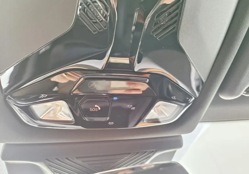 Vue en contre-plongée du plafonnier noir brillant avec bouton SOS et éclairages intégrés dans une BMW Série 1 2025 gris Skyscraper.