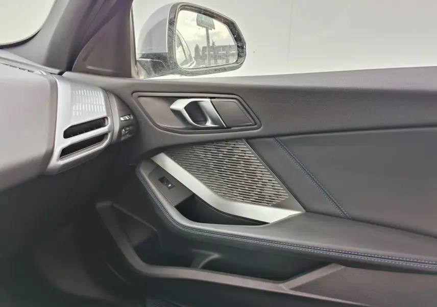 Vue intérieure côté droit de la porte BMW Série 1 F70 avec insert aluminium graphite et surpiqûres bleues.