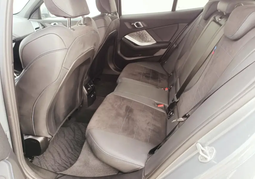 Vue côté droit de la banquette arrière en sellerie Alcantara noire avec surpiqûres bleues dans une BMW Série 1 2025.
