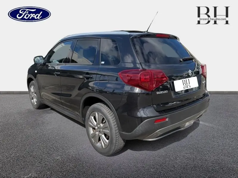 Vue 3/4 arrière droite d'un Suzuki Vitara Cosmic Black Pearl métallisé avec vitres teintées et jantes alu.