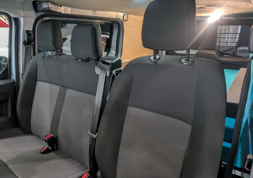 Vue intérieure du Peugeot Expert Fourgon aménagé 2023, sièges avant gris foncé avec habillage bois visible à l'arrière.