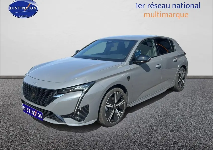 Peugeot 308 gris vue 3/4 avant droit, avec jantes alu et calandre noire distinctive.